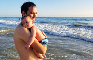 baby with severe eczema at the beach being held by father